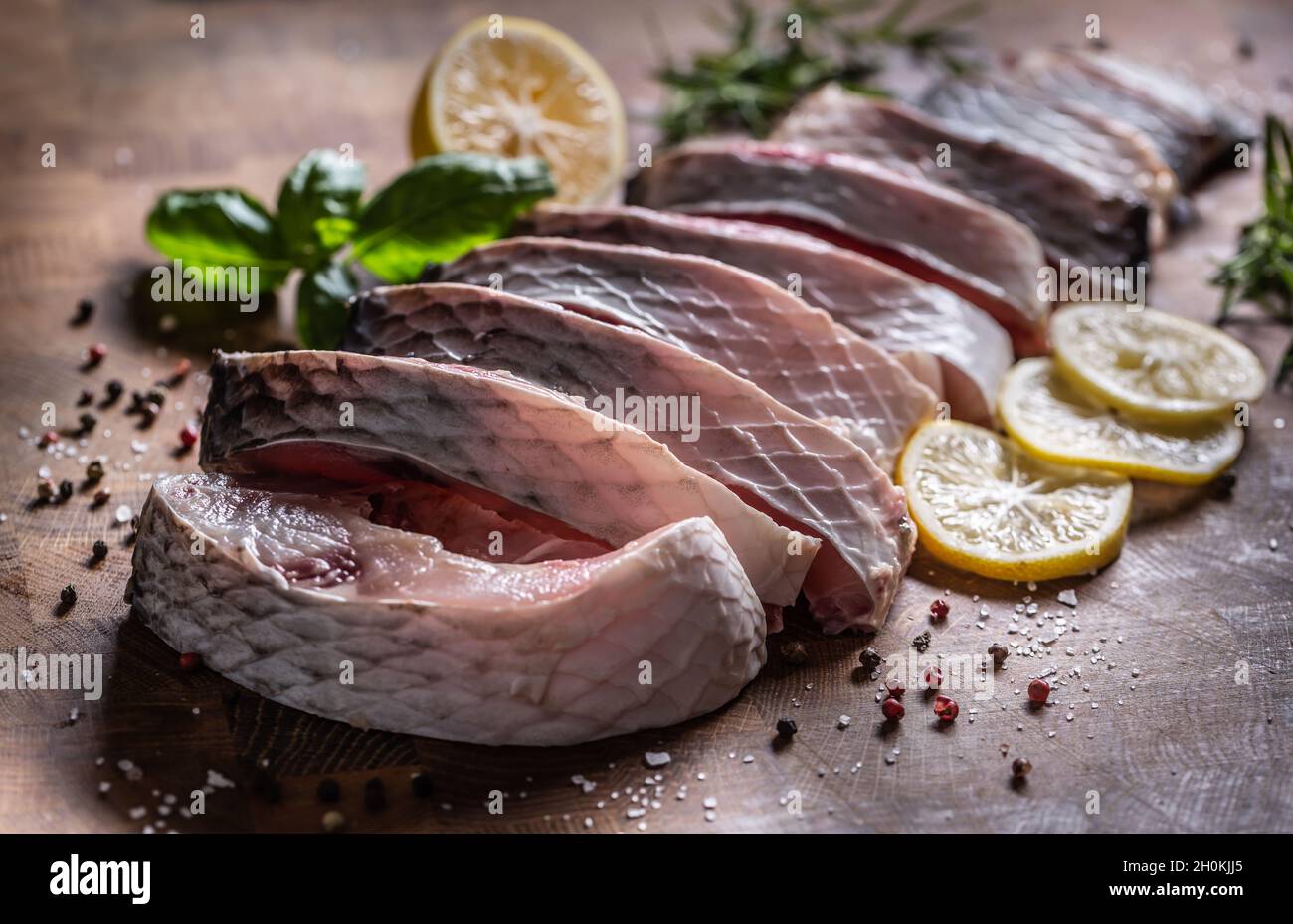 Carpa di pesce porzionata con sale pepe limone ed erbe sul bordo della cucina. Foto Stock