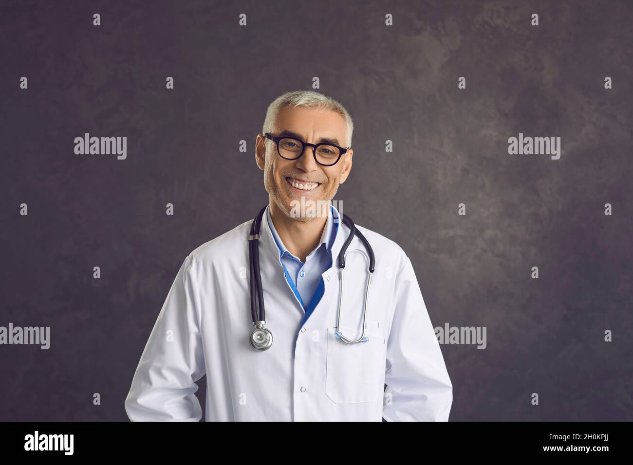 Ritratto di uomo sorridente di mezza età medico in uniforme bianca Foto Stock