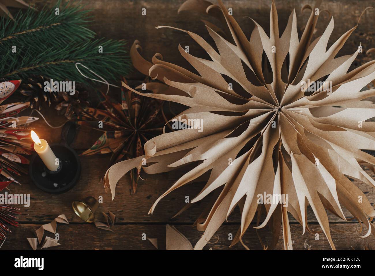 Buon Natale! Elegante carta stella di Natale, candela, ramo di abete rosso e ornamenti su rustico tavolo piatto in legno. Saluto di stagione e avvento di Natale. M Foto Stock