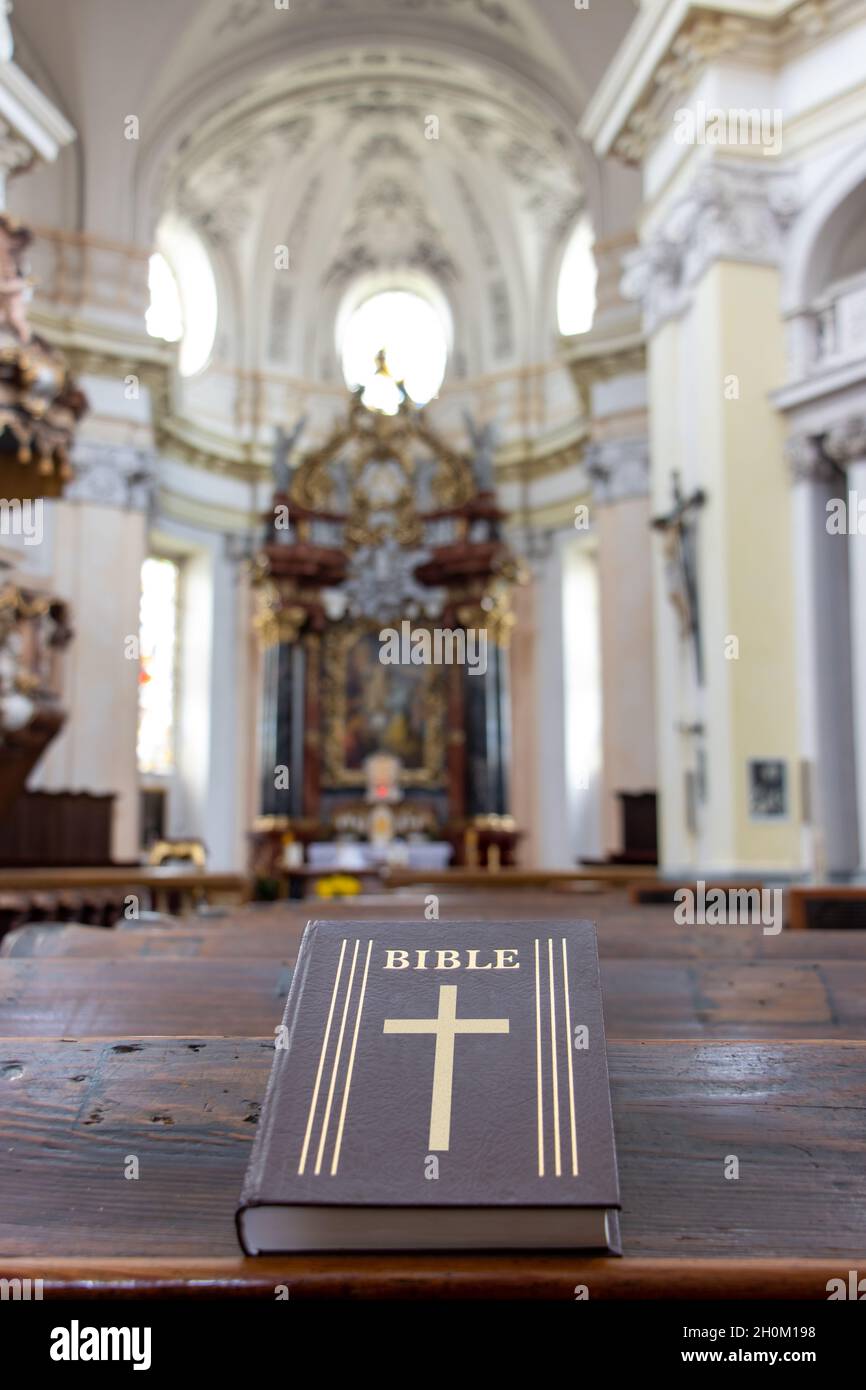 La Bibbia sulla tavola di una panchina di preghiera nella chiesa con un altare. Foto Stock