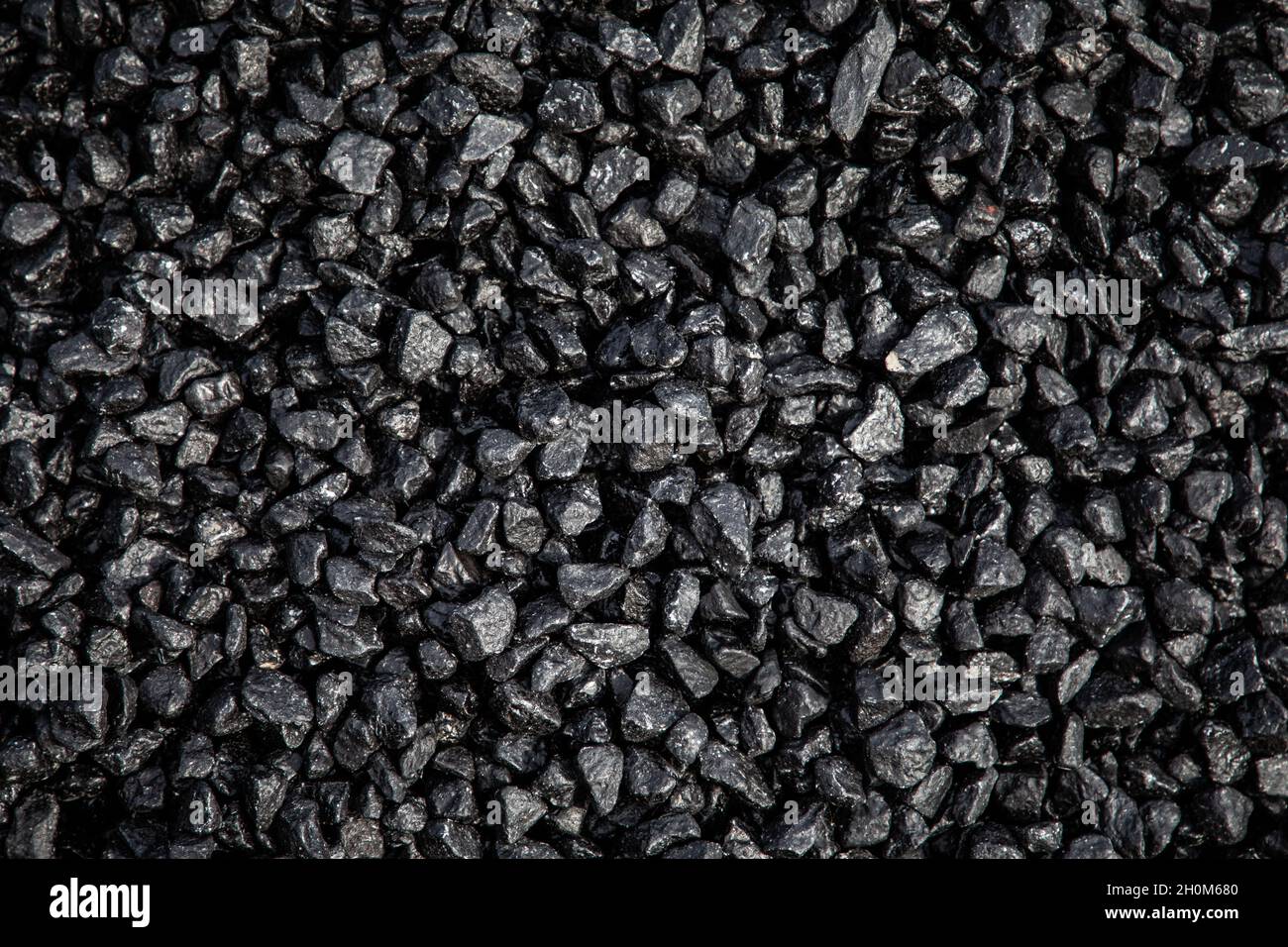 Un mucchio di asfalto fresco di tarmacadam in attesa di essere posato su una superficie stradale Foto Stock