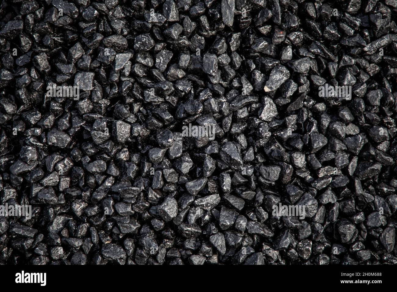 Un mucchio di asfalto fresco di tarmacadam in attesa di essere posato su una superficie stradale Foto Stock