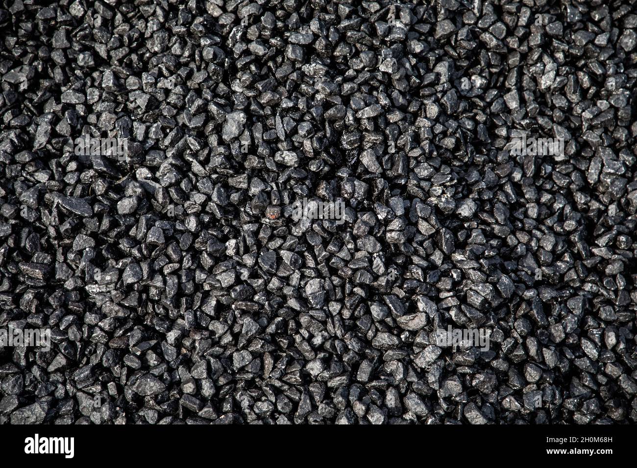 Un mucchio di asfalto fresco di tarmacadam in attesa di essere posato su una superficie stradale Foto Stock