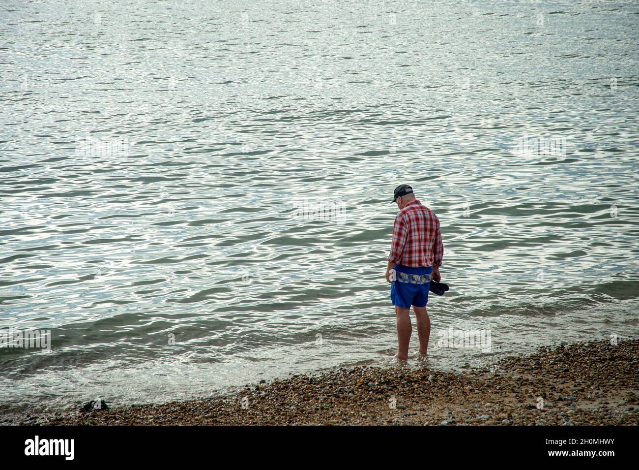 Uomo che cammina in acqua alla spiaggia Foto Stock