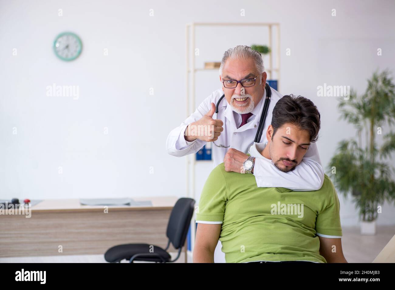 Paziente giovane che visita il medico di sesso maschile anziano Foto Stock