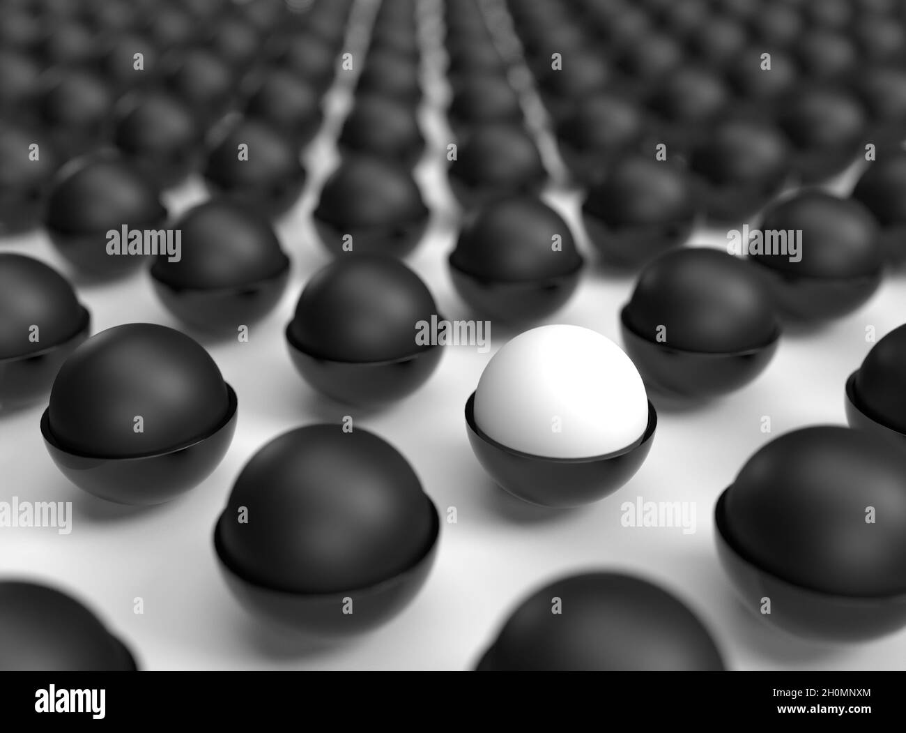Una singola pallina bianca in un campo di palline nere Foto Stock