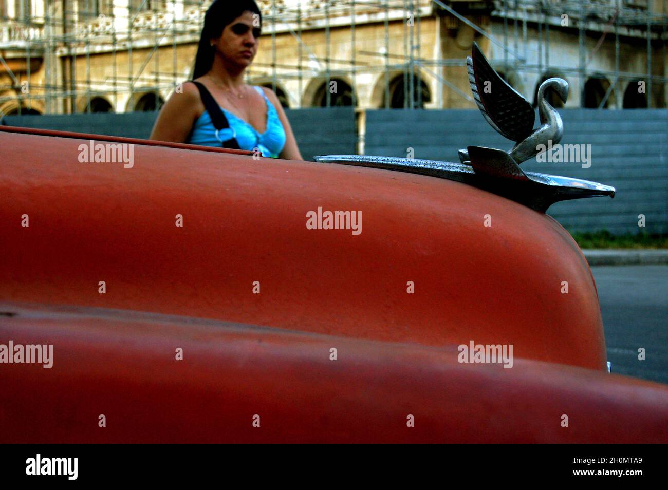 Una signora da una macchina rossa. L'Avana, Cuba. Novembre 27, 2007. Ufficialmente conosciuta come Ciudad de la Habana, è la capitale, il porto principale e il principale centro commerciale di Cuba. La città è una delle 14 province cubane. Ci sono circa 2.4 milioni di abitanti, noti come Habaneros e tra questi quasi 400,000 vivono nella zona urbana rendendo l'Avana la città più grande sia a Cuba che nella regione dei Caraibi. Foto Stock