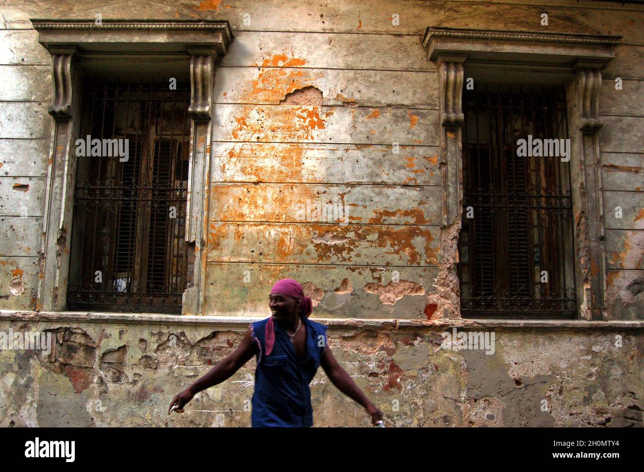 Un uomo contro un vecchio edificio. L'Avana, Cuba. Novembre 27, 2007. Ufficialmente conosciuta come Ciudad de la Habana, è la capitale, il porto principale e il principale centro commerciale di Cuba. La città è una delle 14 province cubane. Ci sono circa 2.4 milioni di abitanti, noti come Habaneros e tra questi quasi 400,000 vivono nella zona urbana rendendo l'Avana la città più grande sia a Cuba che nella regione dei Caraibi. Foto Stock