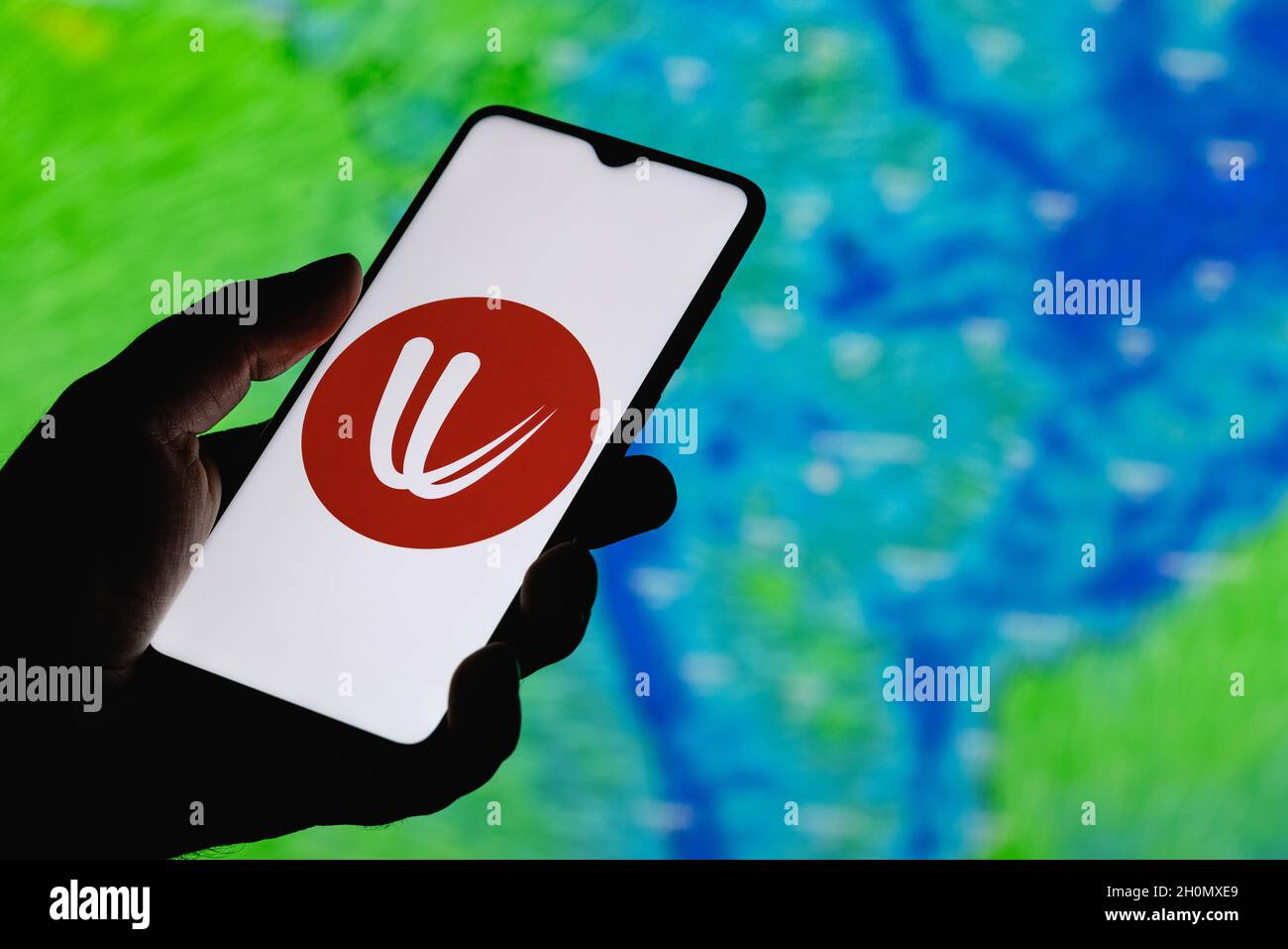 Il vento è un servizio interattivo di previsione meteo in tutto il mondo. Logo ventoso sullo schermo dello smartphone. Sullo sfondo delle previsioni meteo sull'India. Foto Stock