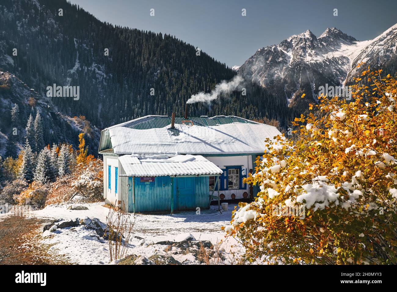 Paesaggio di montagna della foresta autunnale con alberi gialli e neve e casa nel villaggio picco bianco in Kazakistan Foto Stock