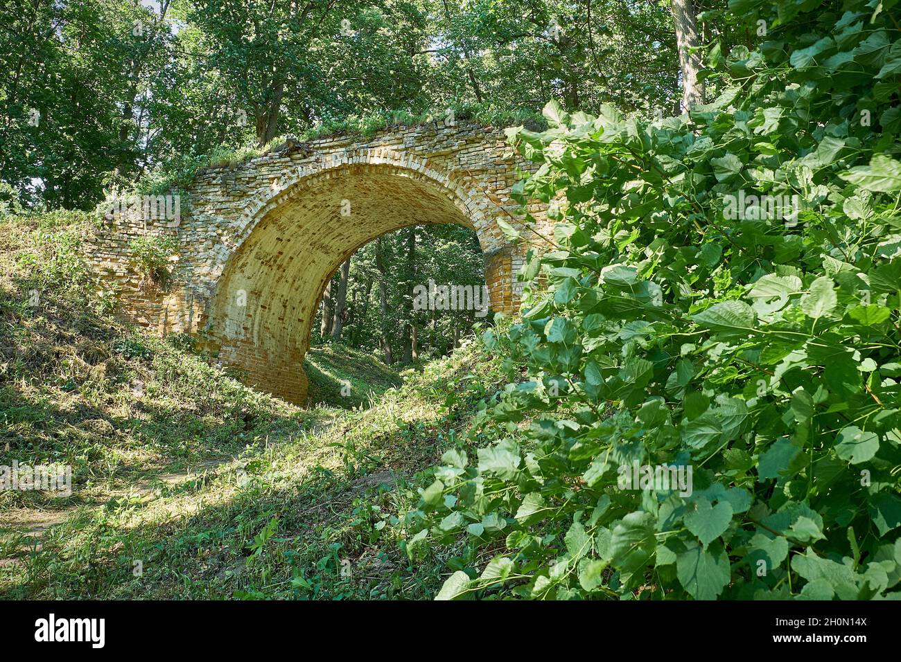 Vecchio ponte ad arco in pietra nel parco estivo Foto Stock