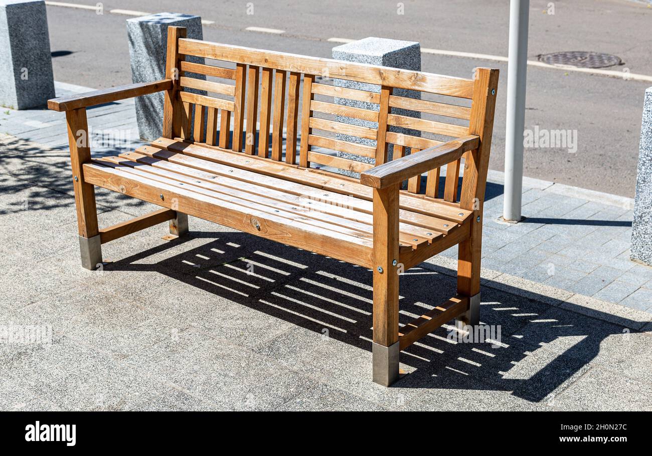 Panca in legno presso la strada di città in estate giornata di sole Foto Stock