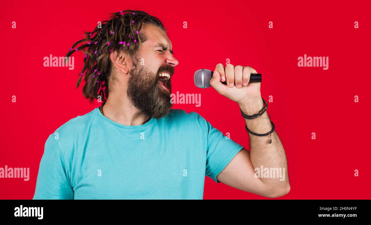 Canto maschile con microfono. Uomo barbuto in karaoke. Cantante emozionale cantare in studio. Musica. Foto Stock