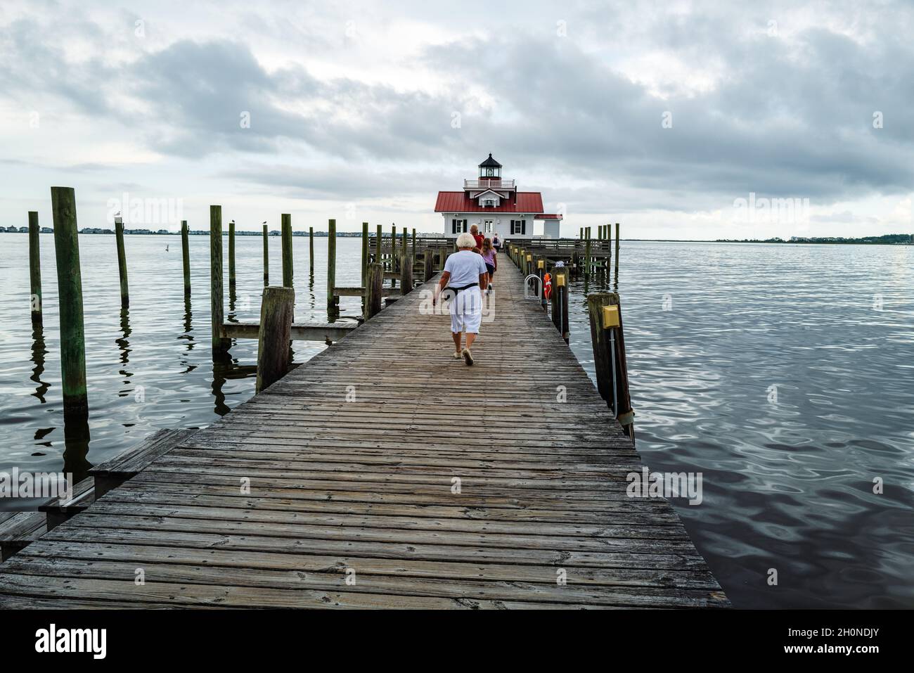 Manteo, NC, USA — 15 agosto 2021. Foto grandangolare persone che camminano sul lungomare che conduce al faro delle paludi di Roanoke. Foto Stock