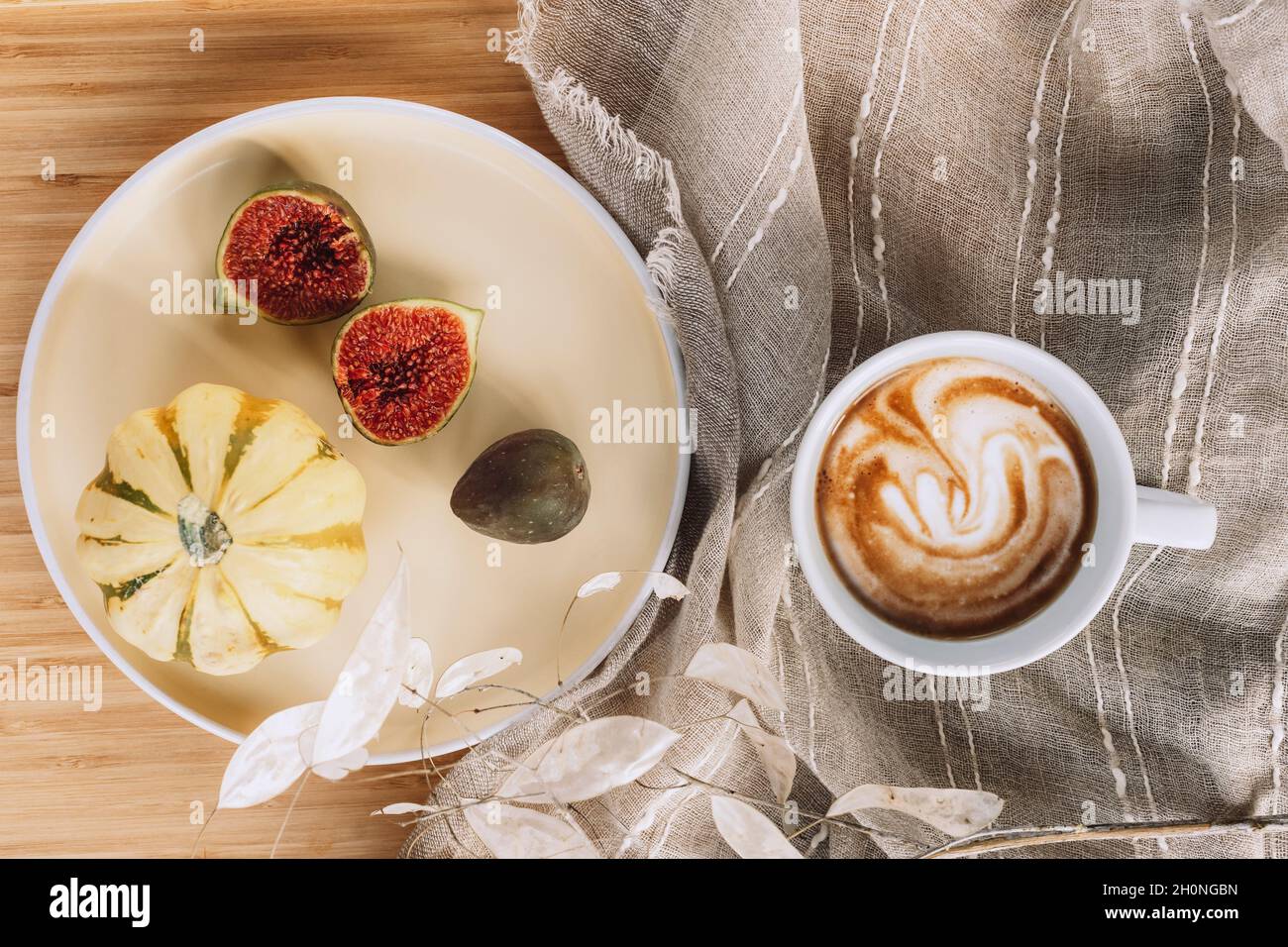 Tazza di caffè latte macchiato e zucca con frutta di fico su un piatto giallo. Appartamento autunno posa, bevanda calda, casa accogliente. Vista dall'alto Foto Stock