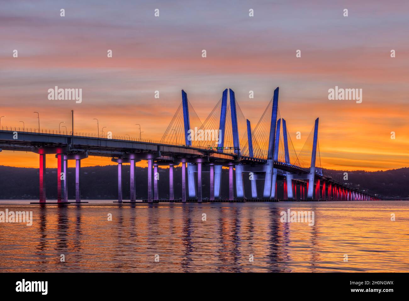 Il Governatore Mario M. Cuomo Bridge, illuminato in rosso, bianco e blu in riconoscimento del Columbus Day, attraversa il fiume Hudson subito dopo il tramonto. Foto Stock