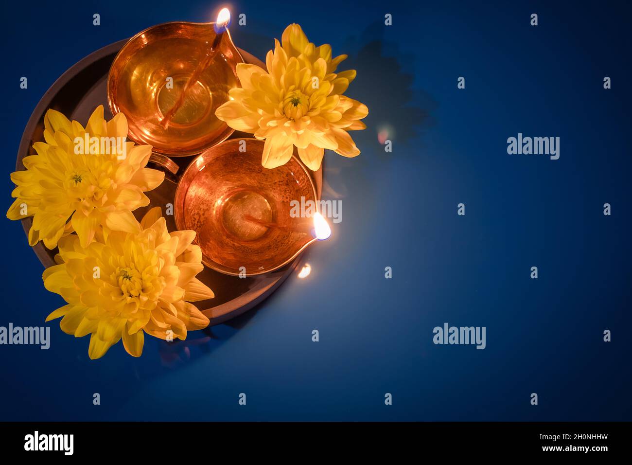 Buon Diwali. Lampade ad olio DIYA e fiori gialli su sfondo blu. Festeggiamo la tradizionale festa indiana della luce. Spazio di copia. Foto Stock