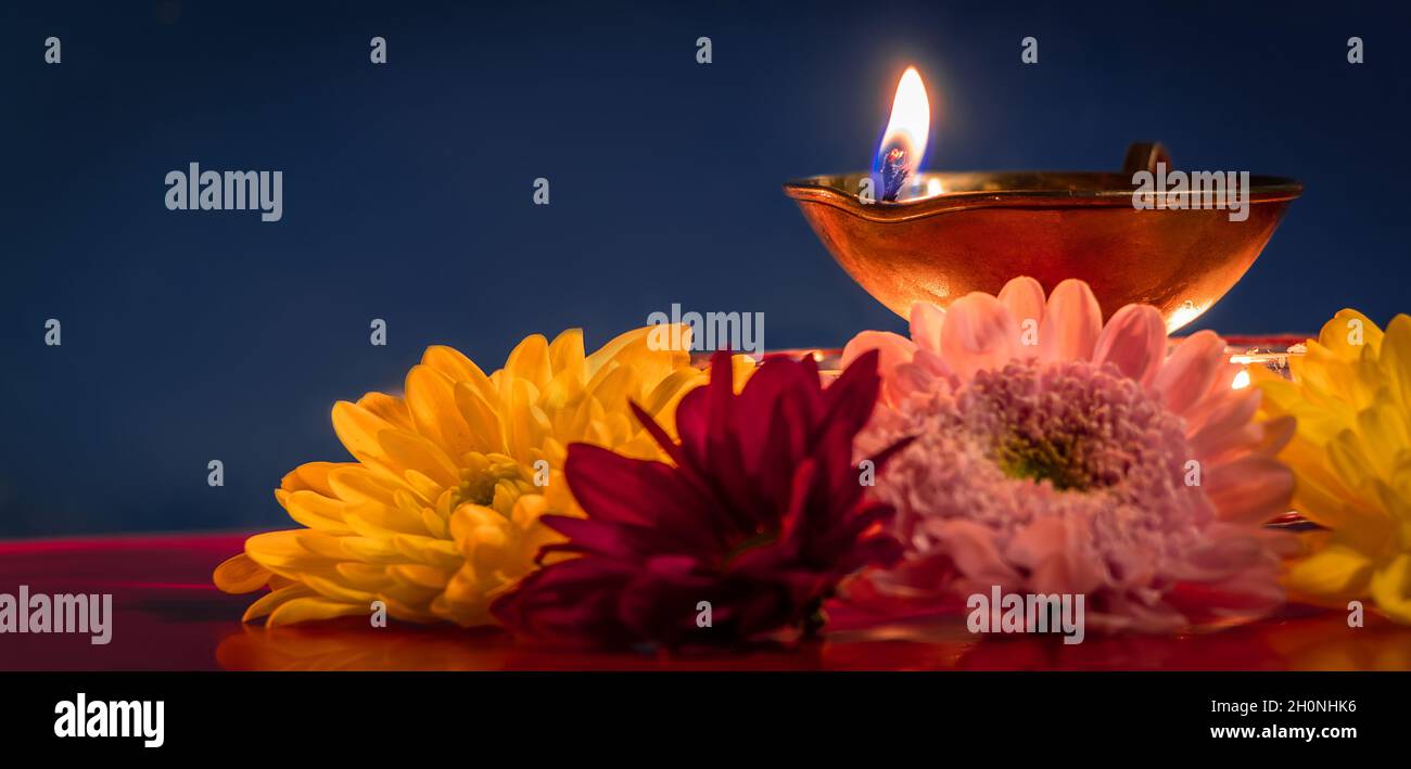 Buon Diwali. Tradizionale festa indiana di luce. Bruciare lampade ad olio di diya e fiori su sfondo rosso. Formato banner. Foto Stock