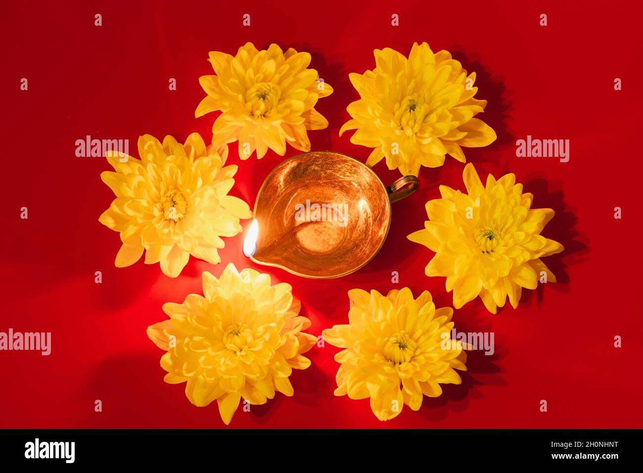 Diwali Indian Light Festival. Lampada ad olio DIYA e fiori gialli su sfondo rosso. Tradizionale celebrazione indù. Spazio di copia. Foto Stock
