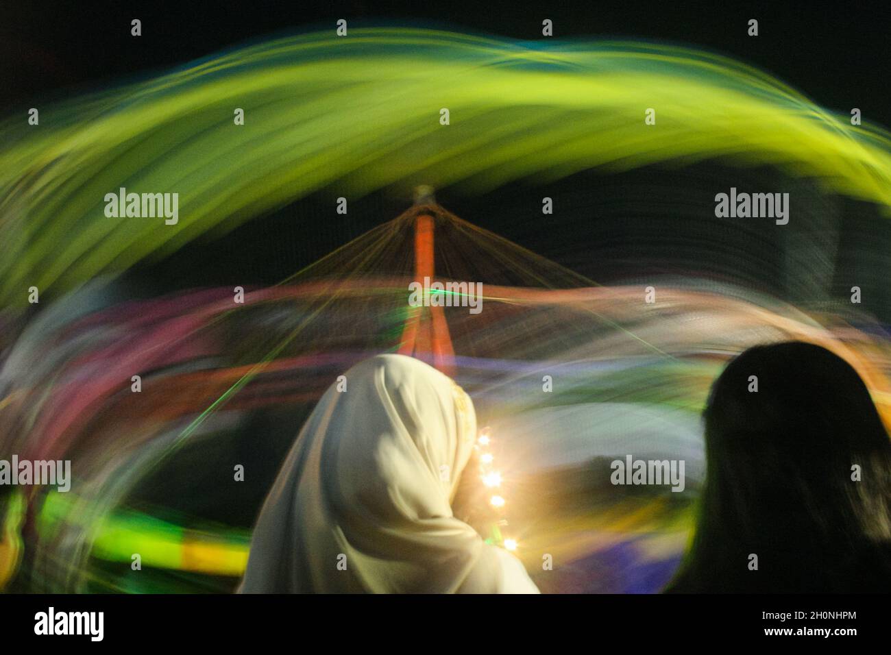 Foto sfocata della luce di Carousel e del pubblico in un mercato notturno. Foto Stock