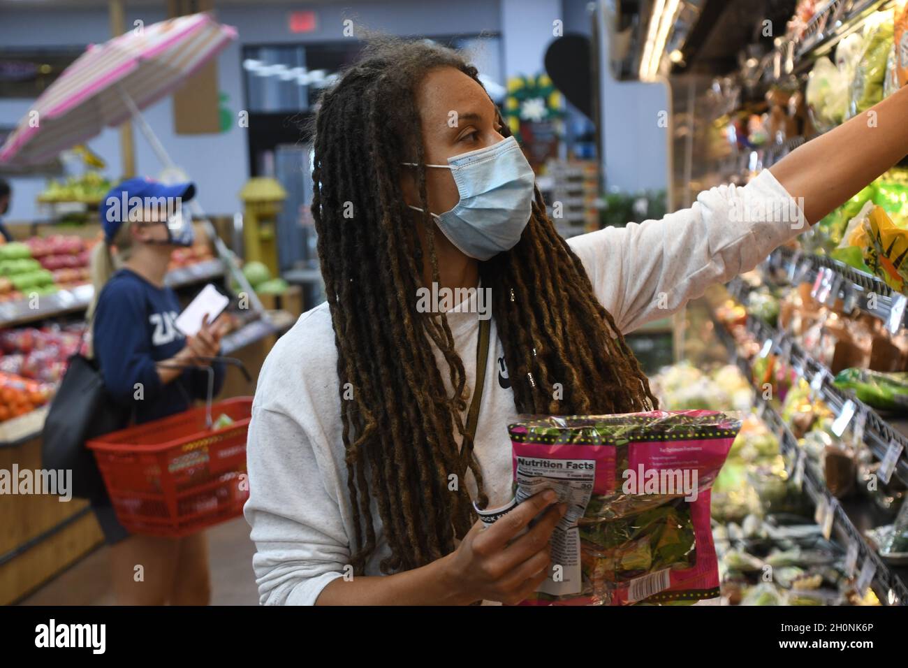 Negozi di donna in un negozio di alimentari durante una pandemia globale di covid-19 in una maschera. Foto Stock