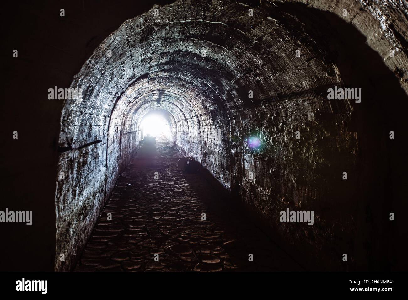 Tunnel sotterraneo scuro. Luce alla fine del tunnel. Foto Stock