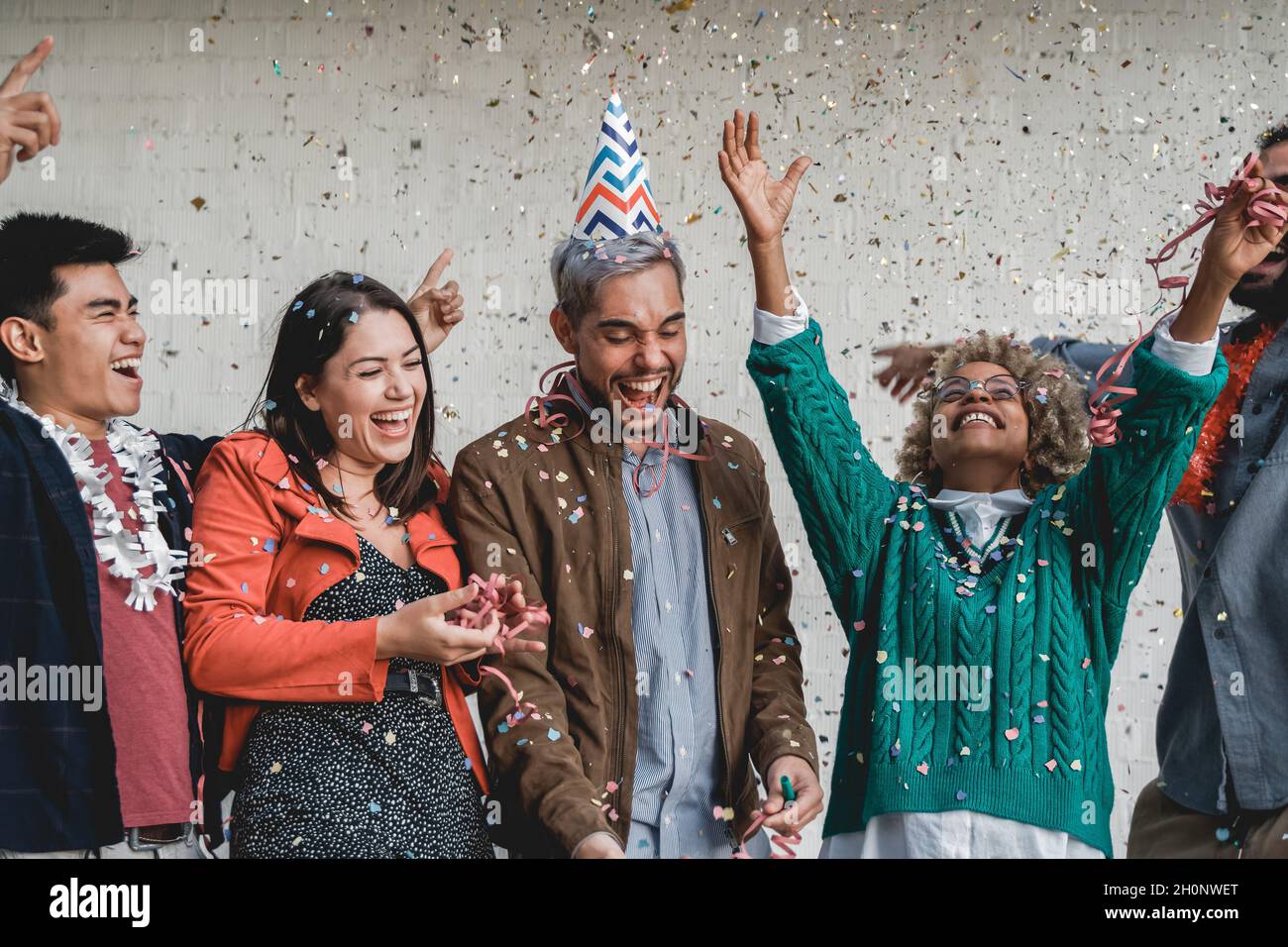 Felice gente multirazziale festeggia con i confetti al compleanno - giovane gruppo di amici divertirsi insieme Foto Stock