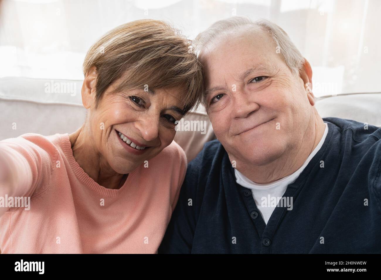 Coppia anziana felice prendendo un selfie con il telefono cellulare a casa - persone reali, concetto di stile di vita anziano Foto Stock