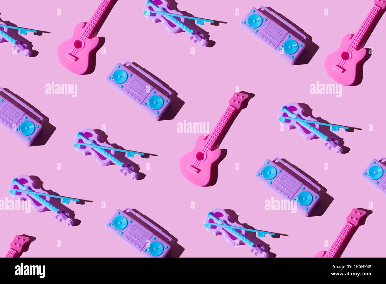 Chitarra giocattolo per bambini, lettore di cassette e violino su sfondo rosa pastello alla moda. Vista dall'alto, disposizione a giacitura piatta. Musica minimale e concetto di festa. Foto Stock