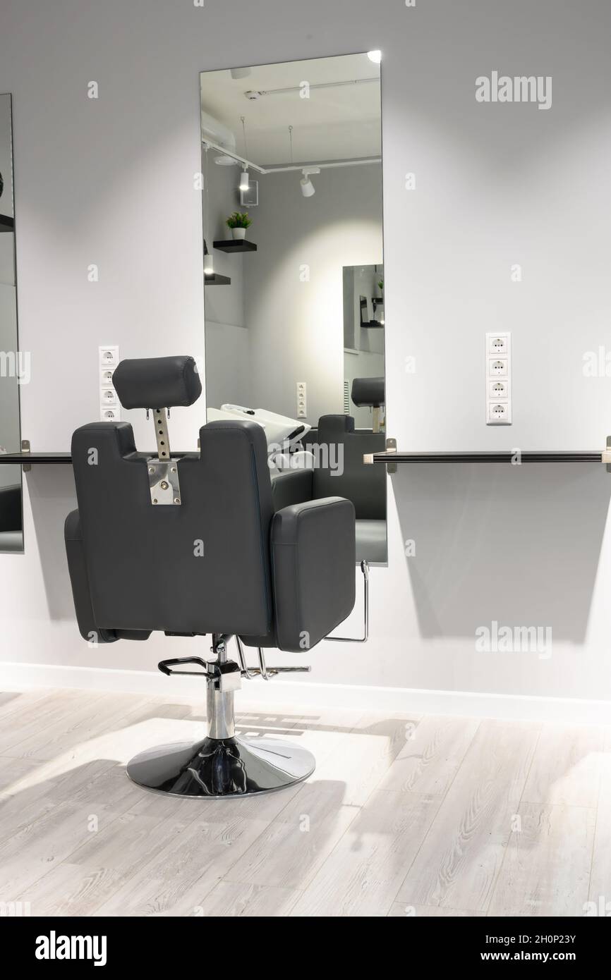 Parrucchiere interno, luogo di lavoro di parrucchiere nel moderno negozio di bellezza dopo la ristrutturazione. Interno barbiere vuoto con specchi e sedia in pelle. Pulire Foto Stock