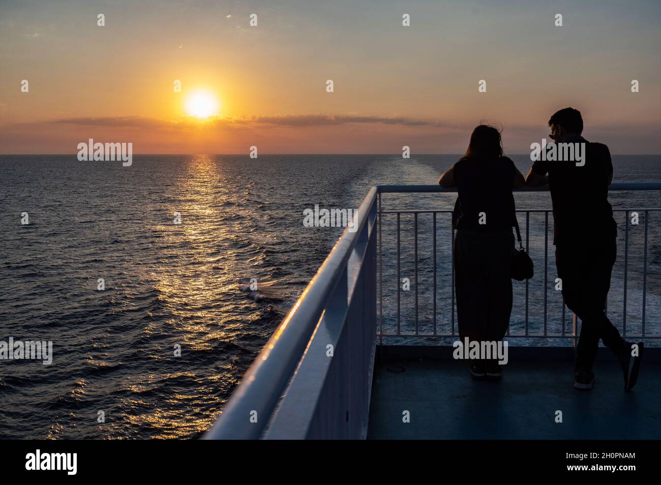 Tramonto sul Mediterraneo vista dal traghetto che collega Tolone e Corsica. Coppia sul ponte con i gomiti che poggiano sulla barriera guardante Foto Stock