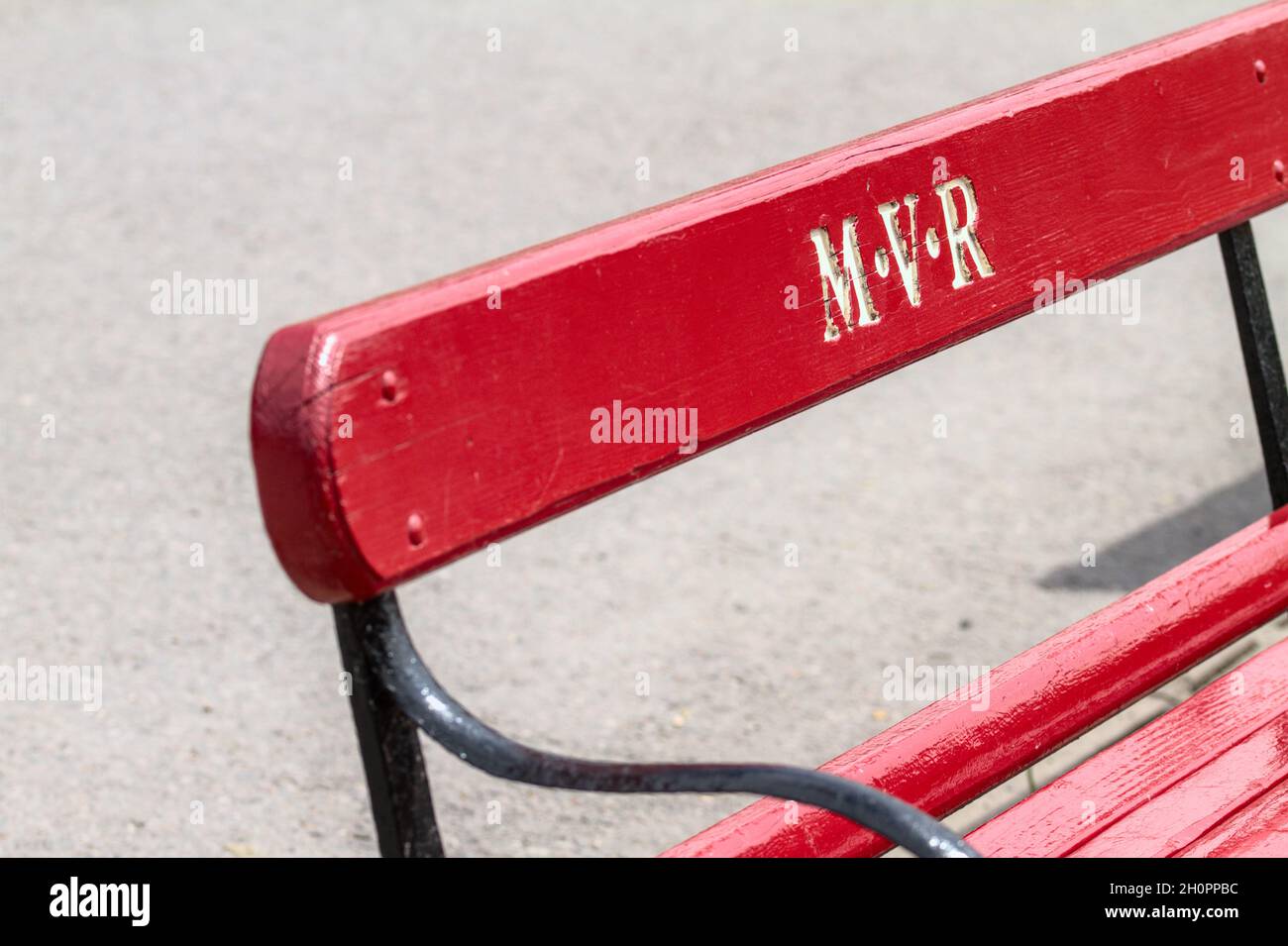 Sedile a panca in legno a doghe rosso con le iniziali intagliate sul retro per la ferrovia in miniatura Moors Valley Foto Stock