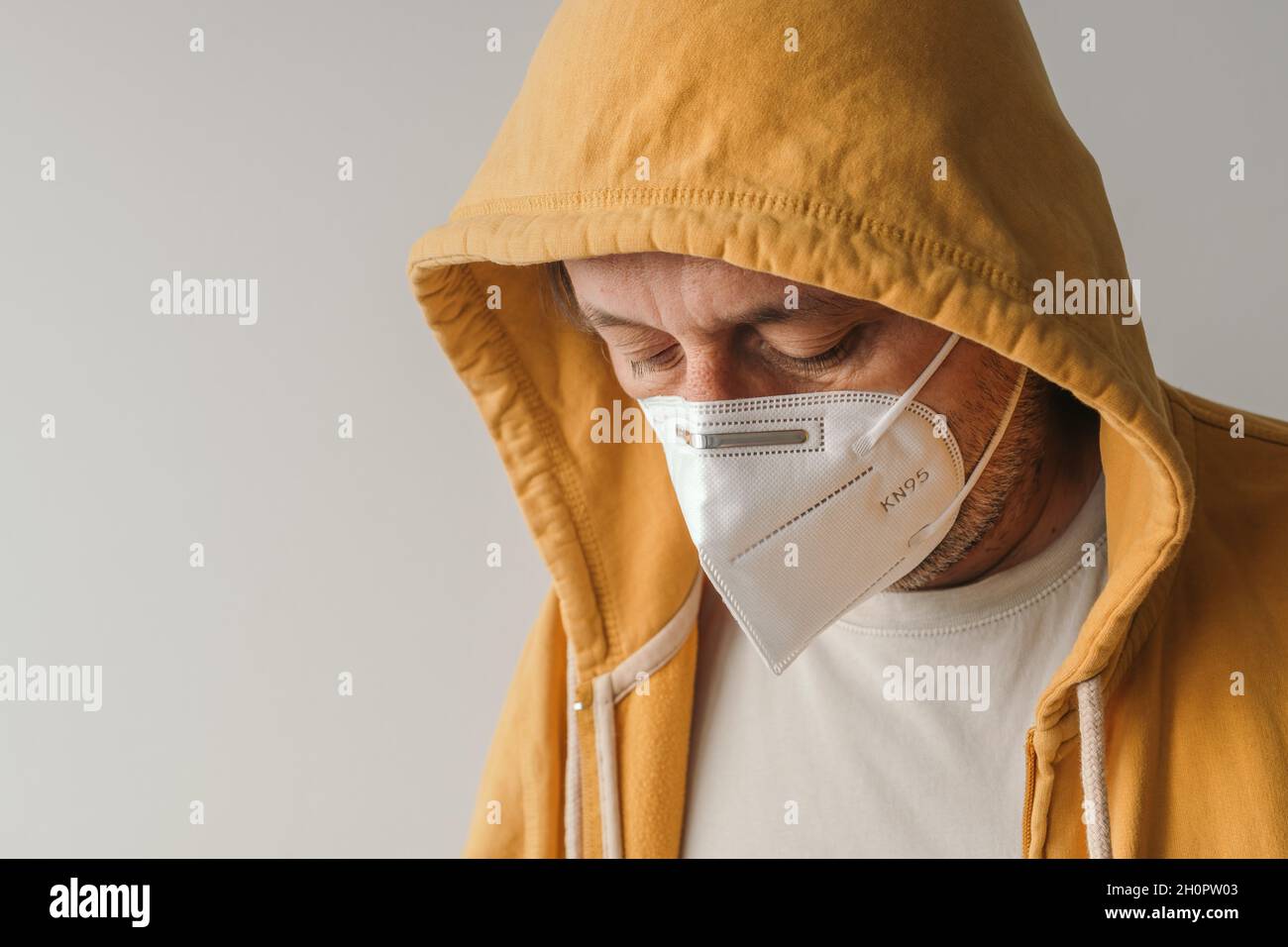 Uomo casual con giacca gialla con cappuccio indossare maschera respiratoria protettiva KN95 durante le pandemie covid-19, fuoco selettivo Foto Stock