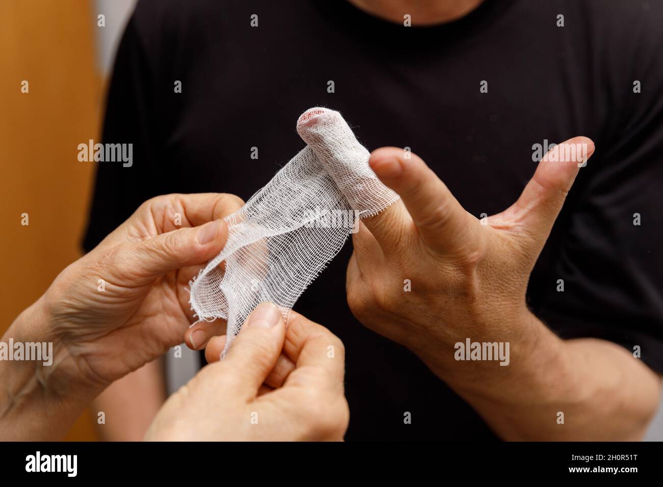 Applicare un bendaggio alla ferita del dito di un uomo. L'uomo trascurò le precauzioni e gli tagliò la mano. Trauma domestico. Lesioni da lavoro. Foto Stock