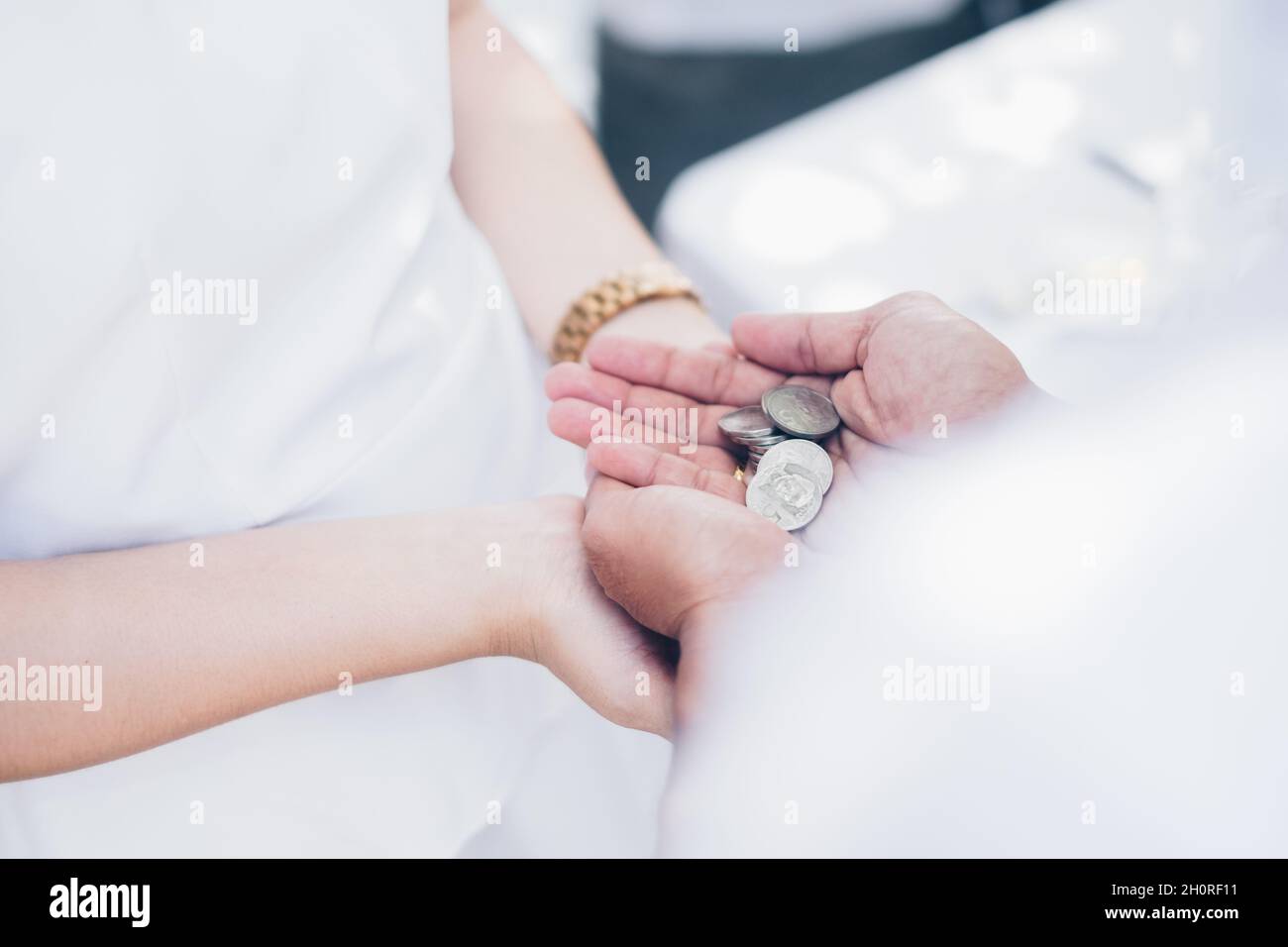 Le palme dello sposo che tengono le monete di unità conosciute come Las Arras o Arrhae sopra le palme della sposa durante la cerimonia nuziale. Messa a fuoco selettiva. Spazio di copia. Foto Stock