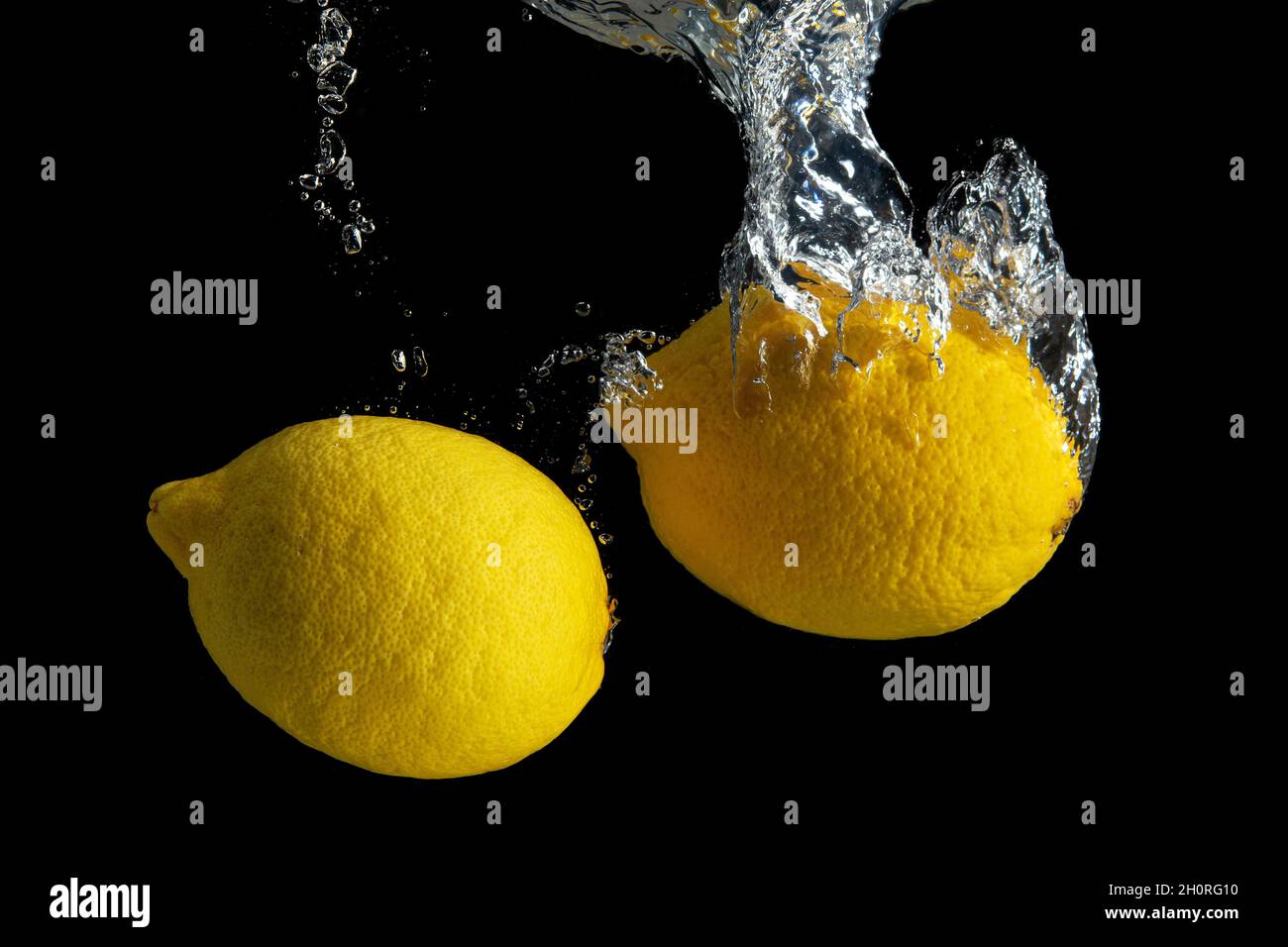 Limone giallo fresco in acqua spruzzata isolato su fondo nero. Concetto di cibo minimo. Foto Stock