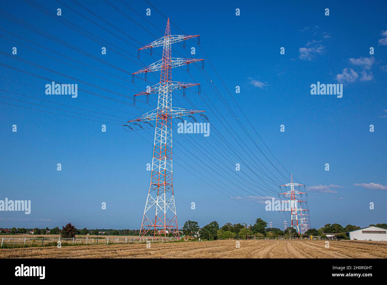Immagine di una grande linea elettrica ad alta tensione con colori di avvertimento e poli ad alta potenza per l'alimentazione in estate Foto Stock