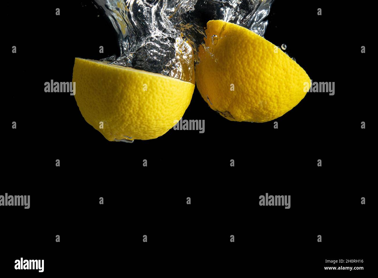 Limone giallo fresco in acqua spruzzata isolato su fondo nero. Concetto di cibo minimo. Foto Stock