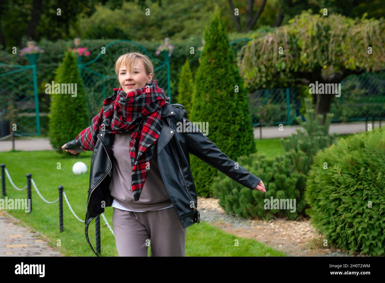 Felice giovane caucasica nel parco autunnale. Donna bionda attraente in piedi in natura con mani aperte Foto Stock