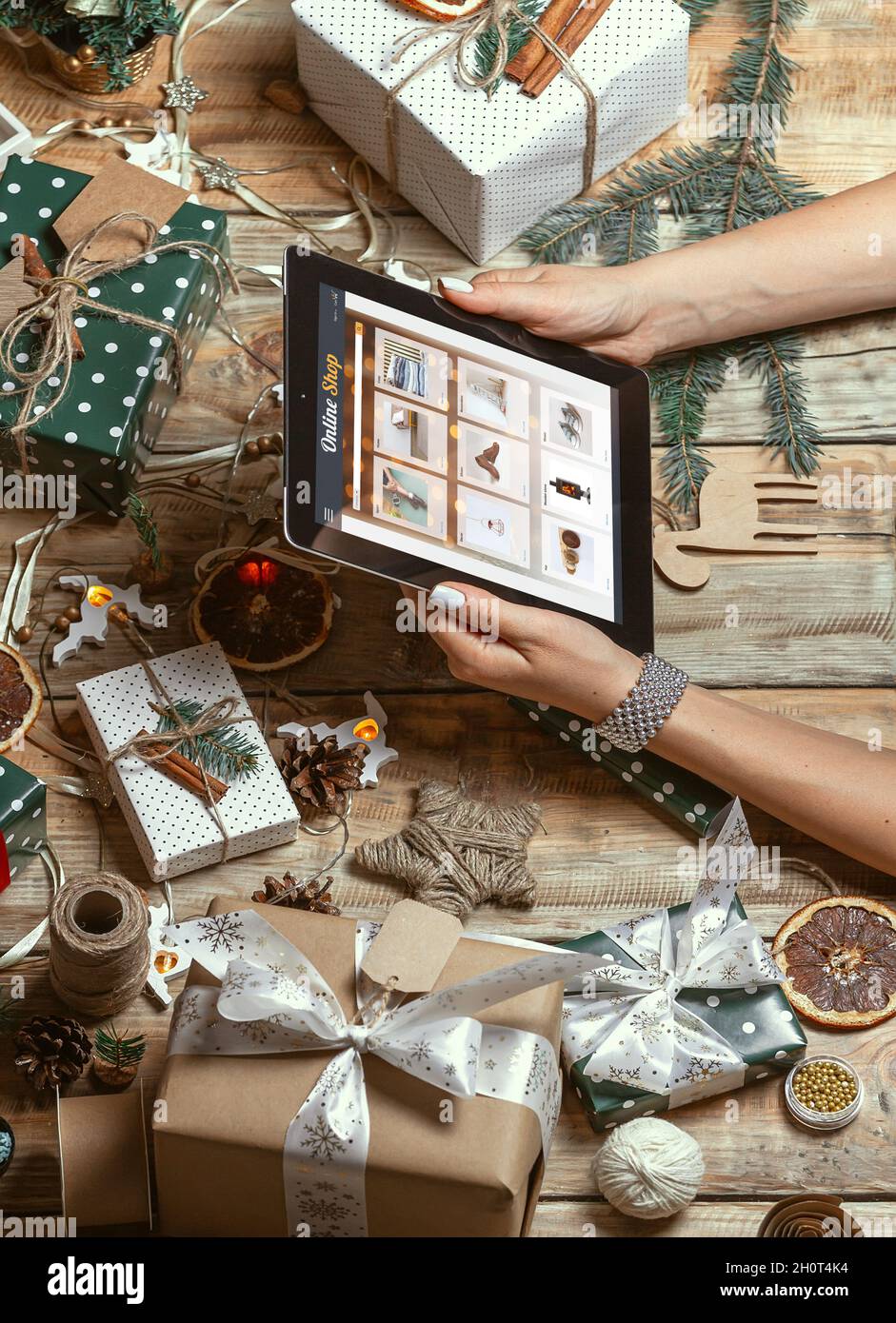 Mani femminili con tablet sul tavolo con decorazioni natalizie fatte a mano Foto Stock