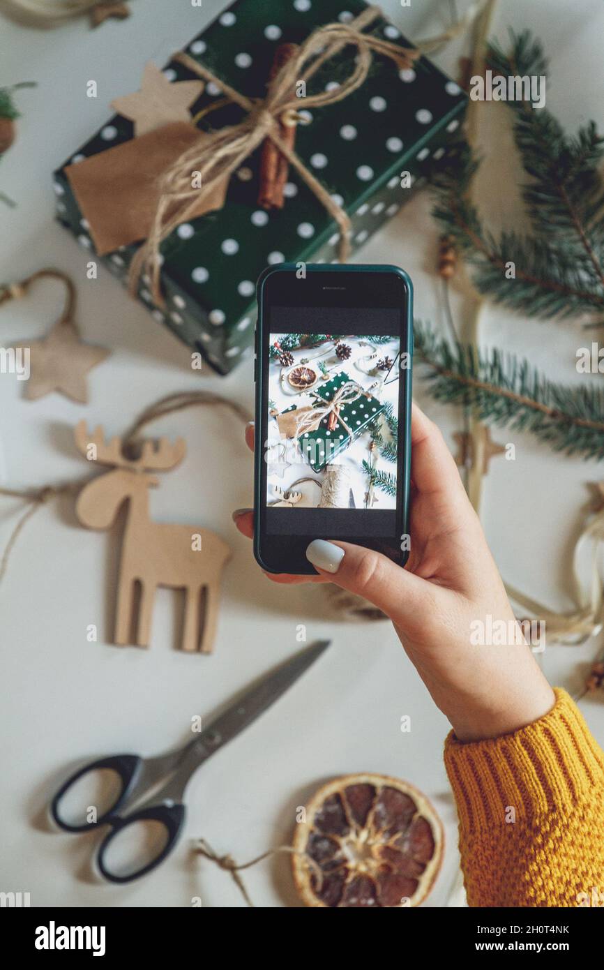 Le mani femminili scattano la foto con il telefono mobile del decoratio di natale Foto Stock