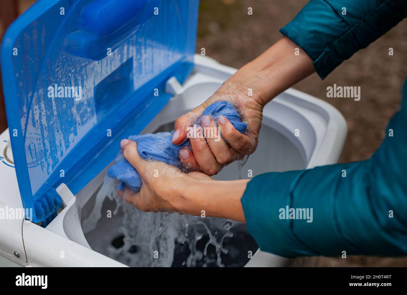le mani strizzano un oggetto umido dopo il lavaggio in lavatrice. Foto di alta qualità Foto Stock