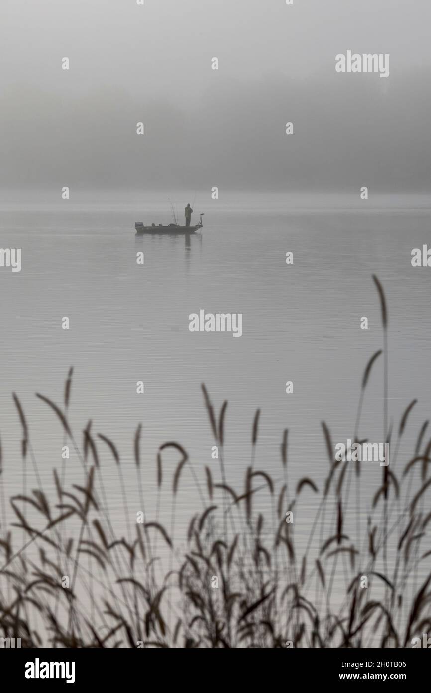 Plainwell, Michigan - Un uomo pesca da una barca sul lago Pine nella nebbia di prima mattina. Foto Stock
