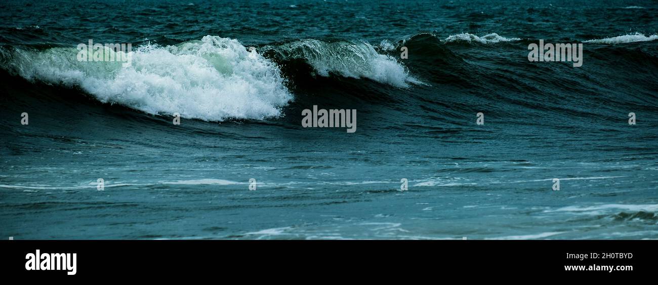 Onde che si infrangono contro rocce al largo della costa di Rhosneigr, Anglesey, Galles del Nord, Regno Unito Foto Stock