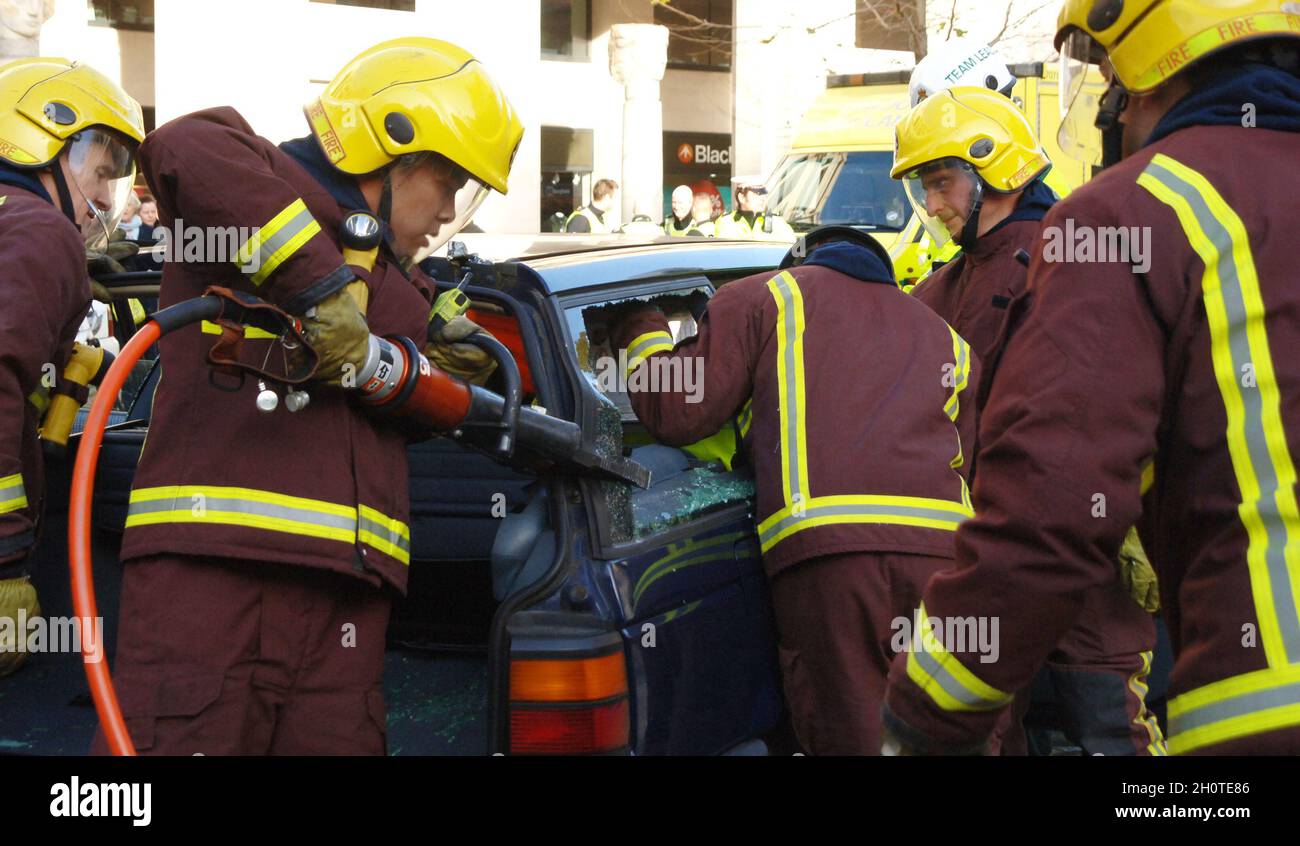 Vigili del fuoco che utilizzano attrezzature idrauliche per liberare un occupante intrappolato di un'auto in seguito a una collisione stradale. Foto Stock