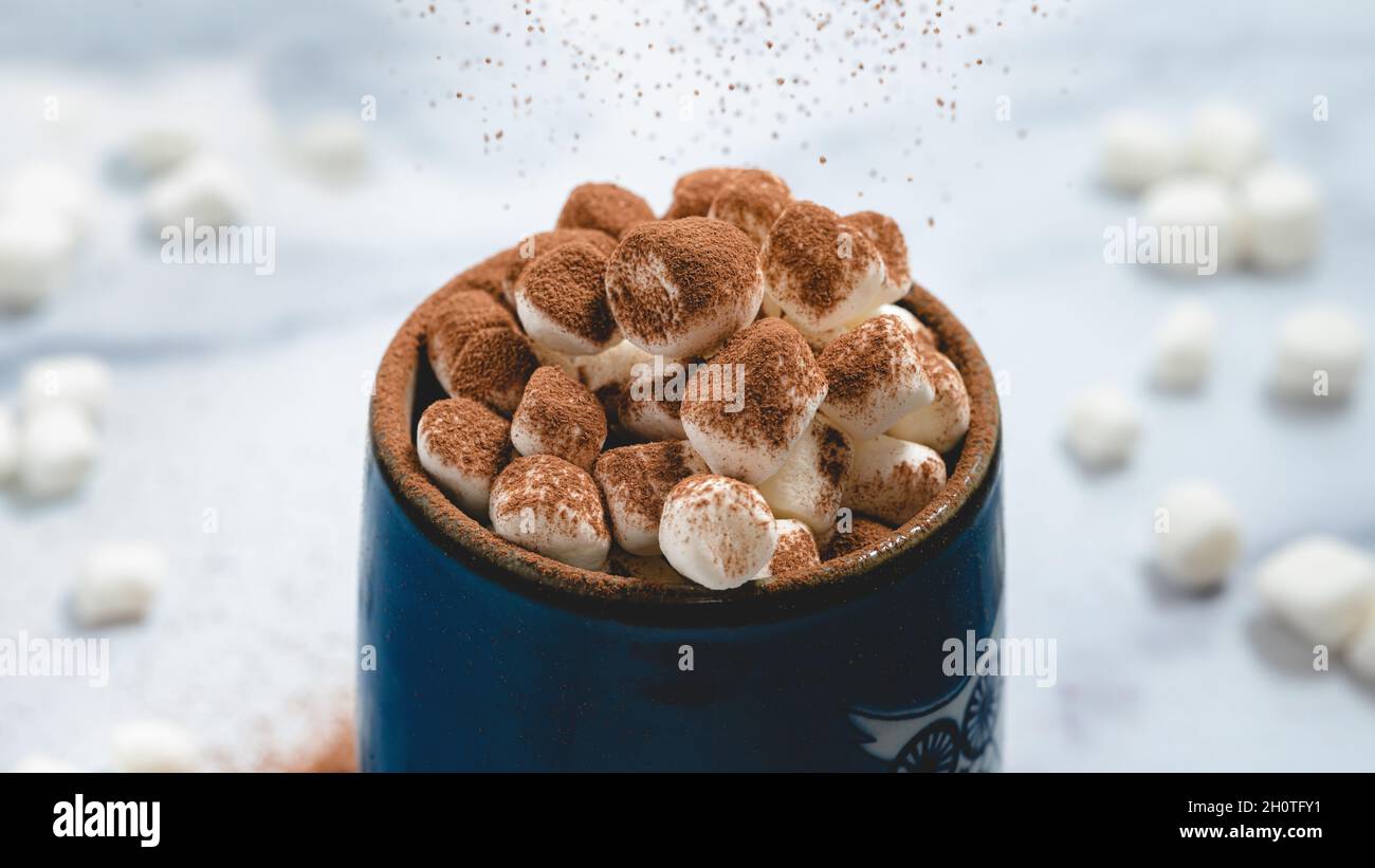 Marshmallow in tazza di caffè con cioccolato in primo piano su sfondo di marmo blu chiaro Foto Stock