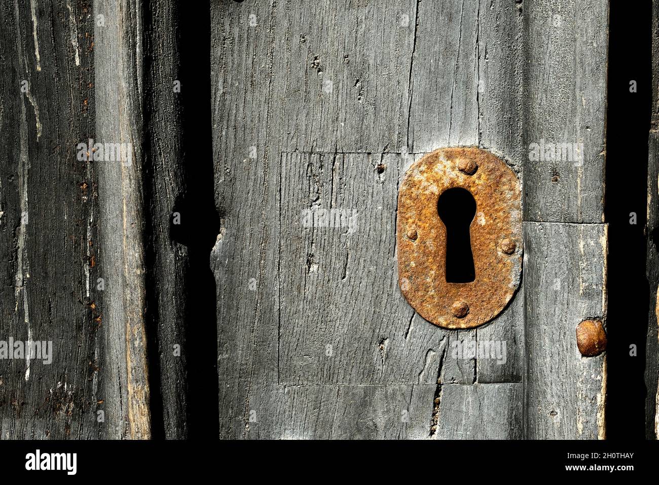 Un primo piano di una vecchia serratura in metallo arrugginito su una vecchia porta in legno Foto Stock