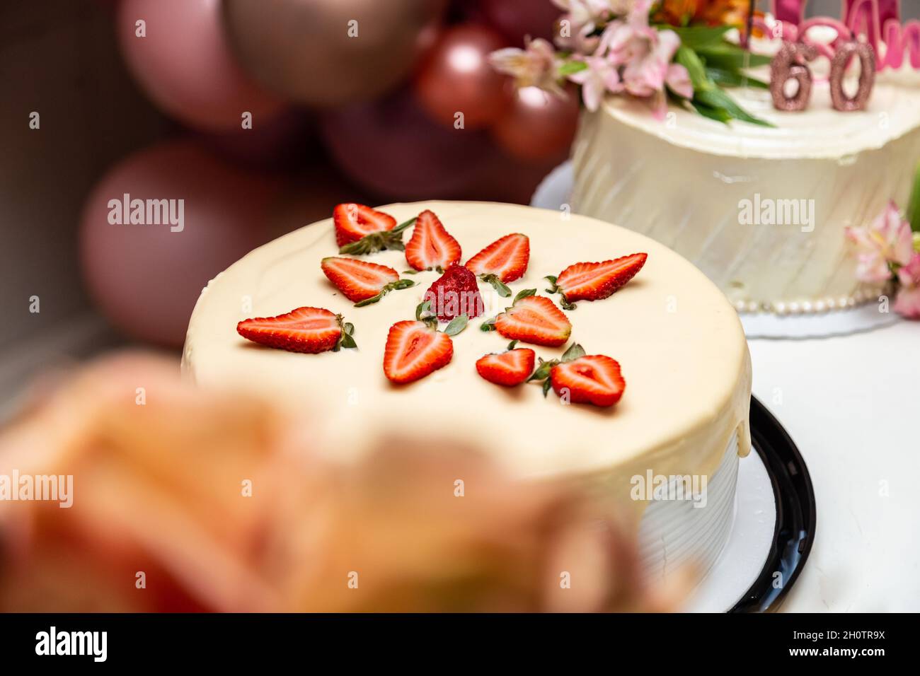 Torta decorata con glassa e fragole su un tavolo decorato per una festa di compleanno. Foto Stock