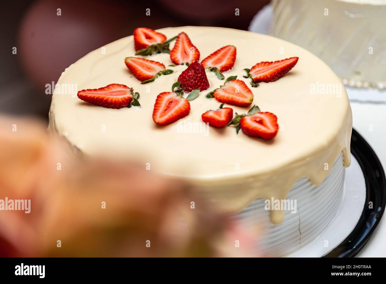 Torta decorata con glassa e fragole su un tavolo decorato per una festa di compleanno. Foto Stock