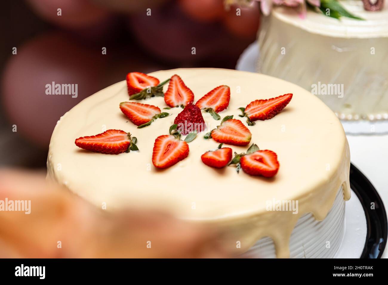 Torta decorata con glassa e fragole su un tavolo decorato per una festa di compleanno. Foto Stock